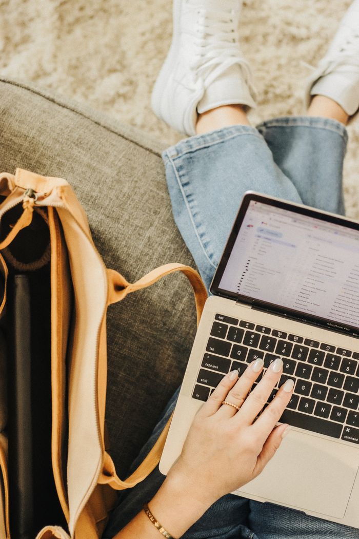 who-we-are A person using a laptop with a stylish tote bag close by in a relaxed setting.